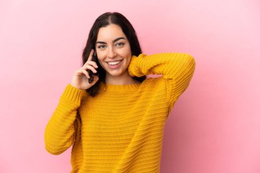 Pembe arka planda izole edilmiş cep telefonu kullanan beyaz bir kadın.