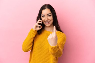 Pembe arka planda izole edilmiş cep telefonu kullanan beyaz bir kadın geliyor.