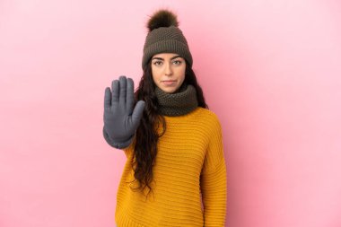 Mor arka planda izole edilmiş, kış şapkalı beyaz kız dur hareketi yapıyor.