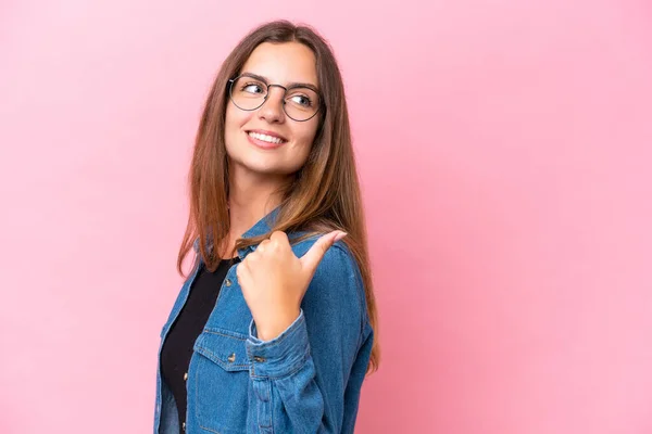 Mujer Joven Caucásica Aislada Sobre Fondo Rosa Apuntando Hacia Lado — Foto de Stock