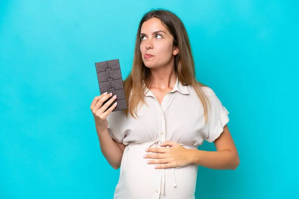 Young Caucasian Woman Isolated Blue Background Pregnant Holding Chocolate Hungry — Stockfoto