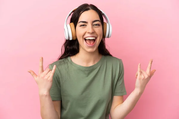 Jovem Caucasiana Isolada Fundo Rosa Ouvindo Música Fazendo Gesto Rock — Fotografia de Stock