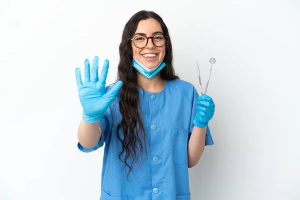 年轻的女牙医拿着在白色背景上隔离的工具 用手指数着五个 — 图库照片
