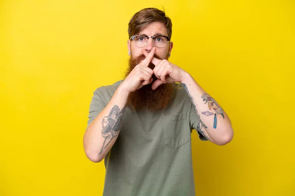 Redhead man with beard isolated on yellow background showing a sign of silence gesture