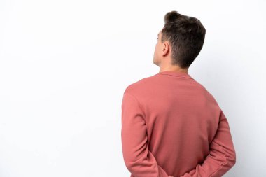 Genç, yakışıklı Brezilyalı bir adam beyaz arka planda izole edilmiş ve arkasına bakıyor.