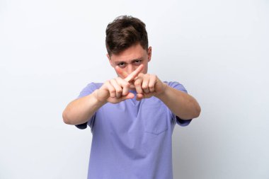 Genç ve yakışıklı Brezilyalı bir adam beyaz arka planda izole edilmiş bir şekilde bir eylemi durdurmak için el hareketi yapıyor.