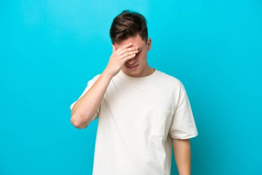 Genç ve yakışıklı Brezilyalı bir adam mavi arka planda başağrısı ile izole edilmiş.
