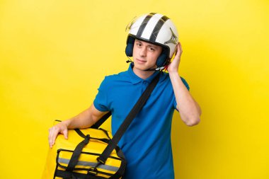 Termal sırt çantalı genç Brezilyalı adam sarı arka planda izole edilmiş. Şüpheleri var.