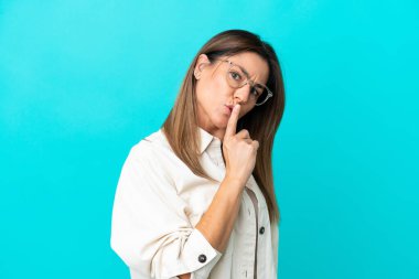 Mavi arka planda, gözlüklü, sessiz hareketler yapan orta yaşlı beyaz bir kadın.