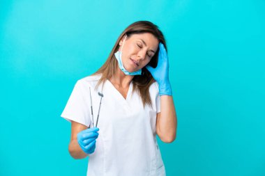 Mavi arka planda baş ağrısı olan orta yaşlı doktor kadın.
