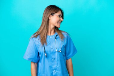 Mavi arka planda izole edilmiş orta yaşlı cerrah kadın.