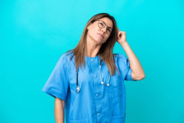 Mavi arka planda izole edilmiş orta yaşlı bir cerrah kadının şüpheleri ve kafa karıştırıcı bir yüz ifadesi var.