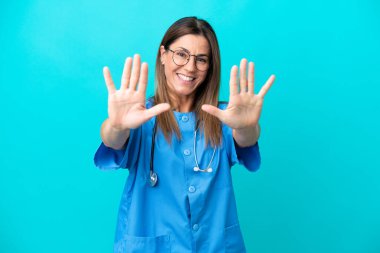 Mavi arka planda izole edilmiş orta yaşlı cerrah kadın parmaklarıyla 10 kişi sayıyor.