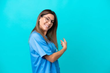 Mavi arka planda izole edilmiş orta yaşlı cerrah kadın.