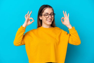 Zen pozunda mavi arka planda izole edilmiş beyaz bir kadın.