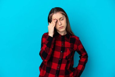 Kafkasyalı genç bir kadın mavi arka planda izole edilmiş, baş ağrısı var.