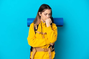 Mavi arka planda izole edilmiş büyük sırt çantalı genç dağcı kadın kuşkuları var.