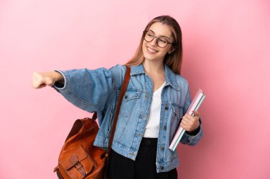 Pembe arka planda izole edilmiş genç beyaz bir bayan baş parmak hareketi yapıyor.