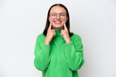 Beyaz arka planda izole edilmiş genç beyaz kadın mutlu ve hoş bir ifadeyle gülümsüyor.