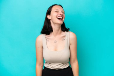 Mavi arka planda izole edilmiş genç beyaz kadın gülüyor.