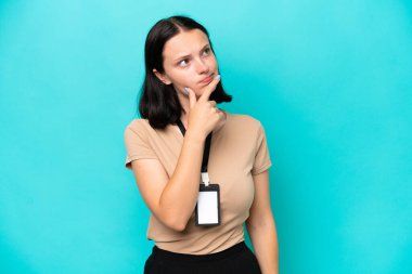 Mavi arka planda izole edilmiş kimliği olan beyaz bir kadın. Şüpheleri var.