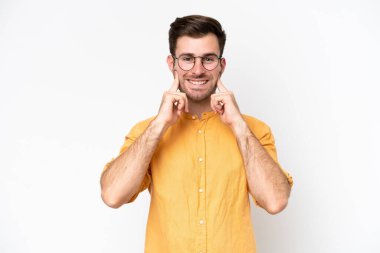 Beyaz arka planda izole edilmiş genç beyaz bir adam mutlu ve hoş bir ifadeyle gülümsüyor.