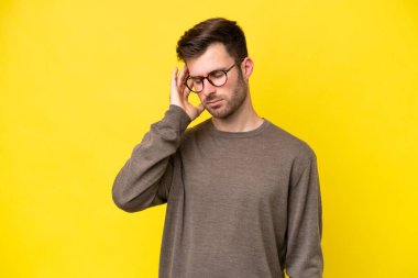 Sarı arka planda başağrısı olan genç beyaz bir adam izole edilmiş.