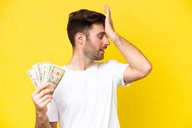 Sarı arka planda izole edilmiş bir sürü para alan genç beyaz adam bir şey fark etti ve çözüme niyetlendi.