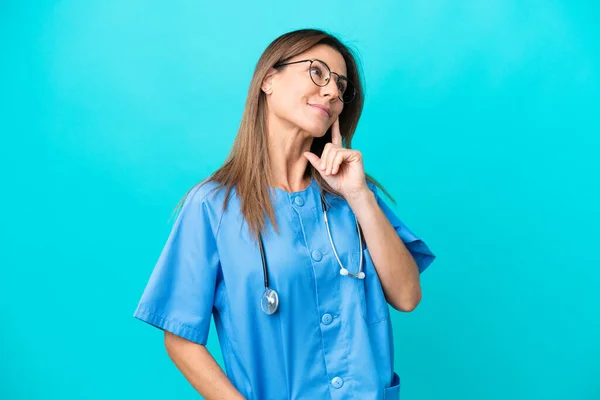 Жінка Хірург Середнього Віку Ізольована Синьому Фоні Думаючи Про Ідею — стокове фото