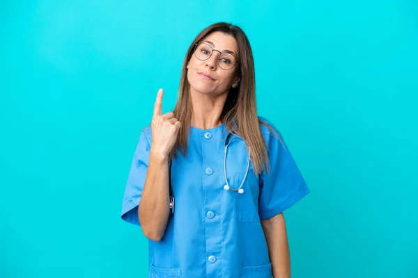 中年妇女外科医生用食指将蓝色背景隔离是一个很好的主意 — 图库照片