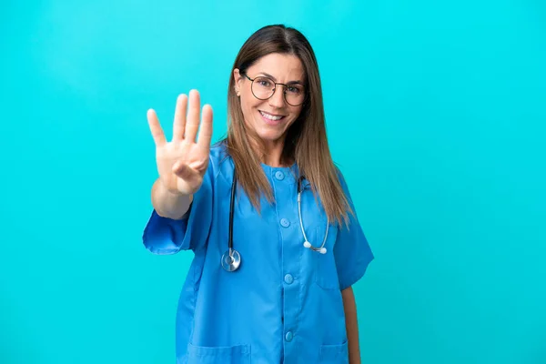 Chirurg Średnim Wieku Kobieta Odizolowana Niebieskim Tle Szczęśliwy Liczyć Cztery — Zdjęcie stockowe