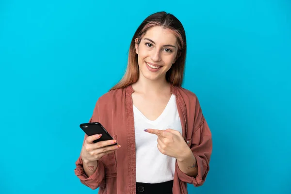 Giovane Donna Caucasica Isolata Sfondo Blu Utilizzando Telefono Cellulare Indicandolo — Foto Stock