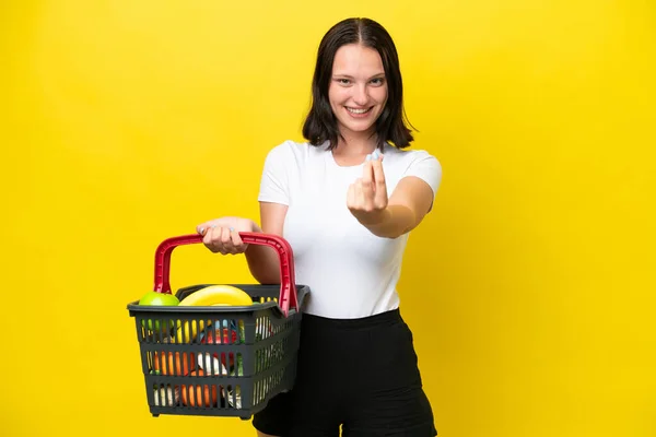 Junge Frau Hält Einen Einkaufskorb Voller Lebensmittel Auf Gelbem Hintergrund — Stockfoto