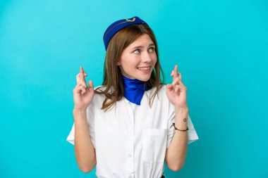 Uçak hostesi İngiliz kadın mavi arka planda izole edilmiş ve şans diliyor.