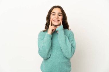 Beyaz arka planda izole edilmiş küçük beyaz kız mutlu ve hoş bir ifadeyle gülümsüyor.