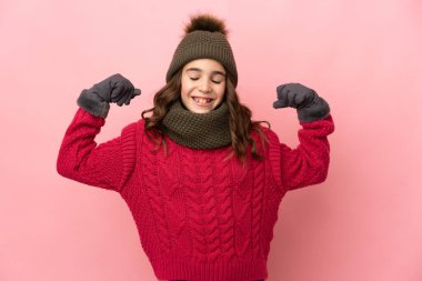 Pembe arka planda izole edilmiş küçük bir kız güçlü bir jest yapıyor.