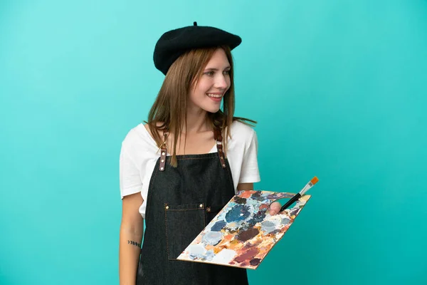 Młoda Artystka Angielska Kobieta Trzyma Paletę Odizolowanych Niebieskim Tle Patrząc — Zdjęcie stockowe