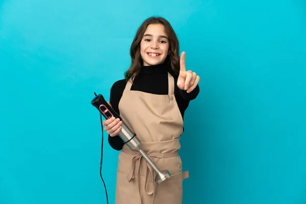 Menina Usando Liquidificador Mão Isolado Fundo Azul Mostrando Levantando Dedo — Fotografia de Stock