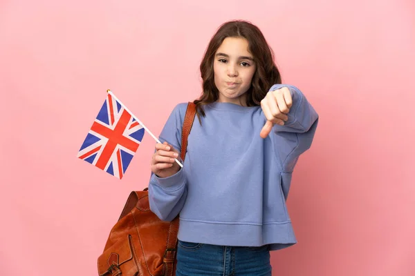 拿着英国国旗的小女孩 粉色背景孤立 带着负面表情垂下大拇指 — 图库照片