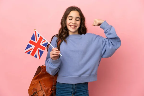 拿着英国国旗的小女孩 背景是粉色的 做着强有力的手势 — 图库照片