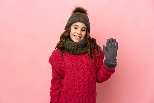 Κοριτσάκι Χειμωνιάτικο Καπέλο Απομονωμένο Ροζ Φόντο Χαιρετώντας Χέρι Χαρούμενη Έκφραση — Φωτογραφία Αρχείου