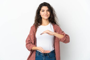 Beyaz arka planda izole edilmiş genç bir Rus kızı, bir ilan vermek için avucunda hayali bir mekan tutuyor.