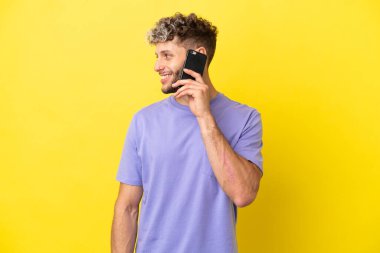 Sarı arka planda izole edilmiş cep telefonu kullanan beyaz bir adam.