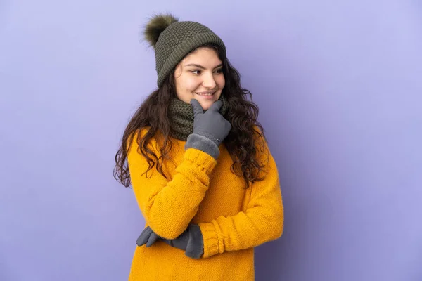 俄罗斯少女 头戴冬帽 背景紫色 向侧面看去 面带微笑 — 图库照片