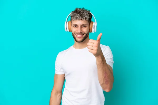Νεαρός Όμορφος Καυκάσιος Άνδρας Απομονωμένος Μπλε Φόντο Ακούγοντας Μουσική Και — Φωτογραφία Αρχείου