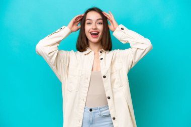 Genç Ukraynalı kadın, mavi arka planda, sürpriz bir ifadeyle izole edilmiş.