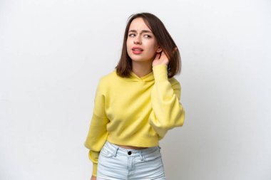 Genç Ukraynalı bir kadın beyaz arka planda izole edilmiş bir şekilde elini kulağına koyarak bir şeyler dinliyor.