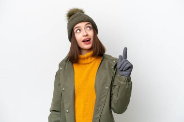 Young Ukrainian woman wearing winter jacket isolated on white background pointing up and surprised