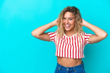 Kıvırcık saçlı kız mavi arka planda yalnız gülüyor.