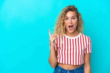 Mavi arka planda izole edilmiş kıvırcık saçlı kız parmağını kaldırarak çözümü bulmaya çalışıyor.